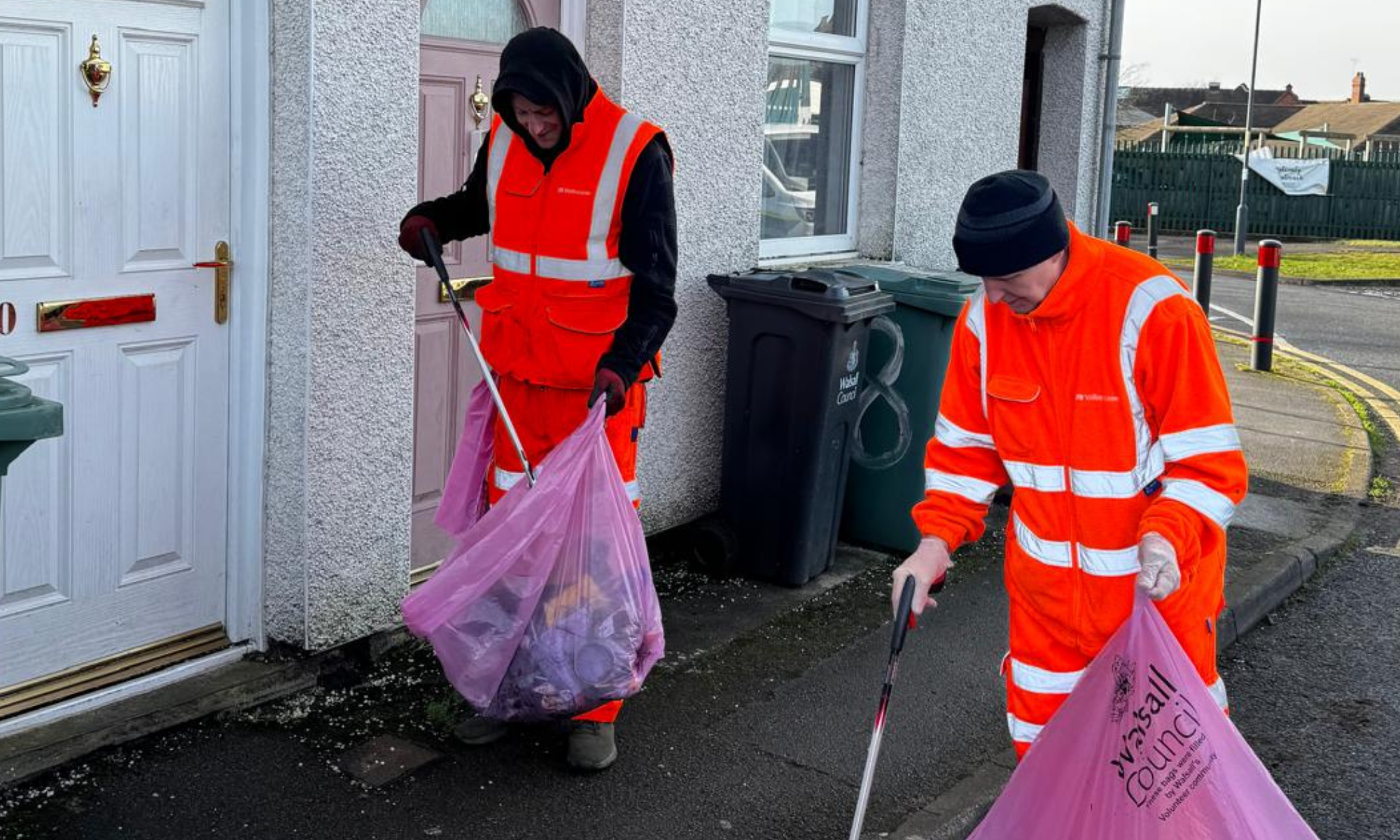 2 men in orange hi-vis clothing litter picking